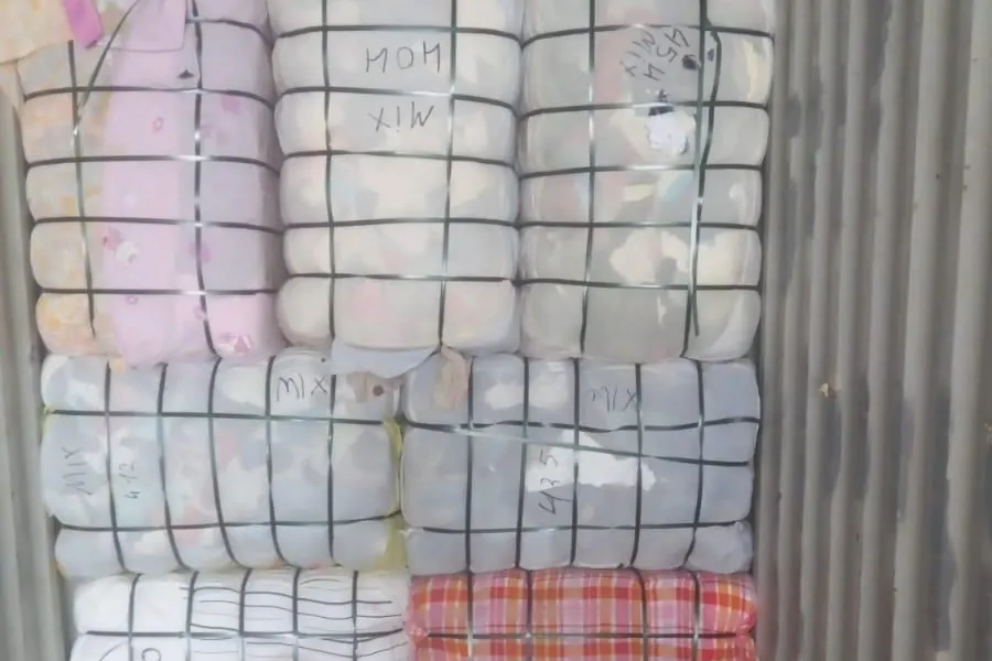 Mixed clothing bales marked by hand inside a container