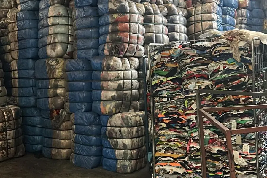 Bales in our warehouse next to a cage of sorted garments ready for baling